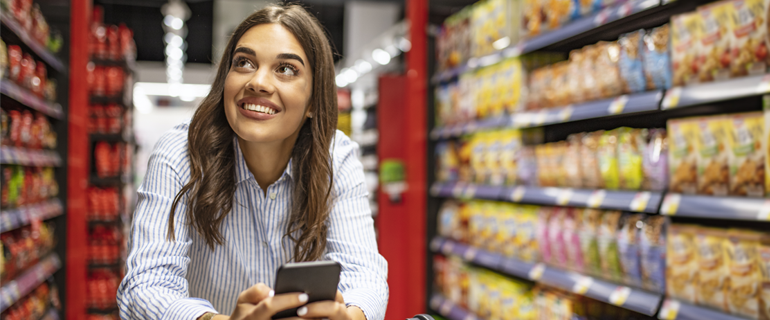 Ragazza al supermercato con smartphone 